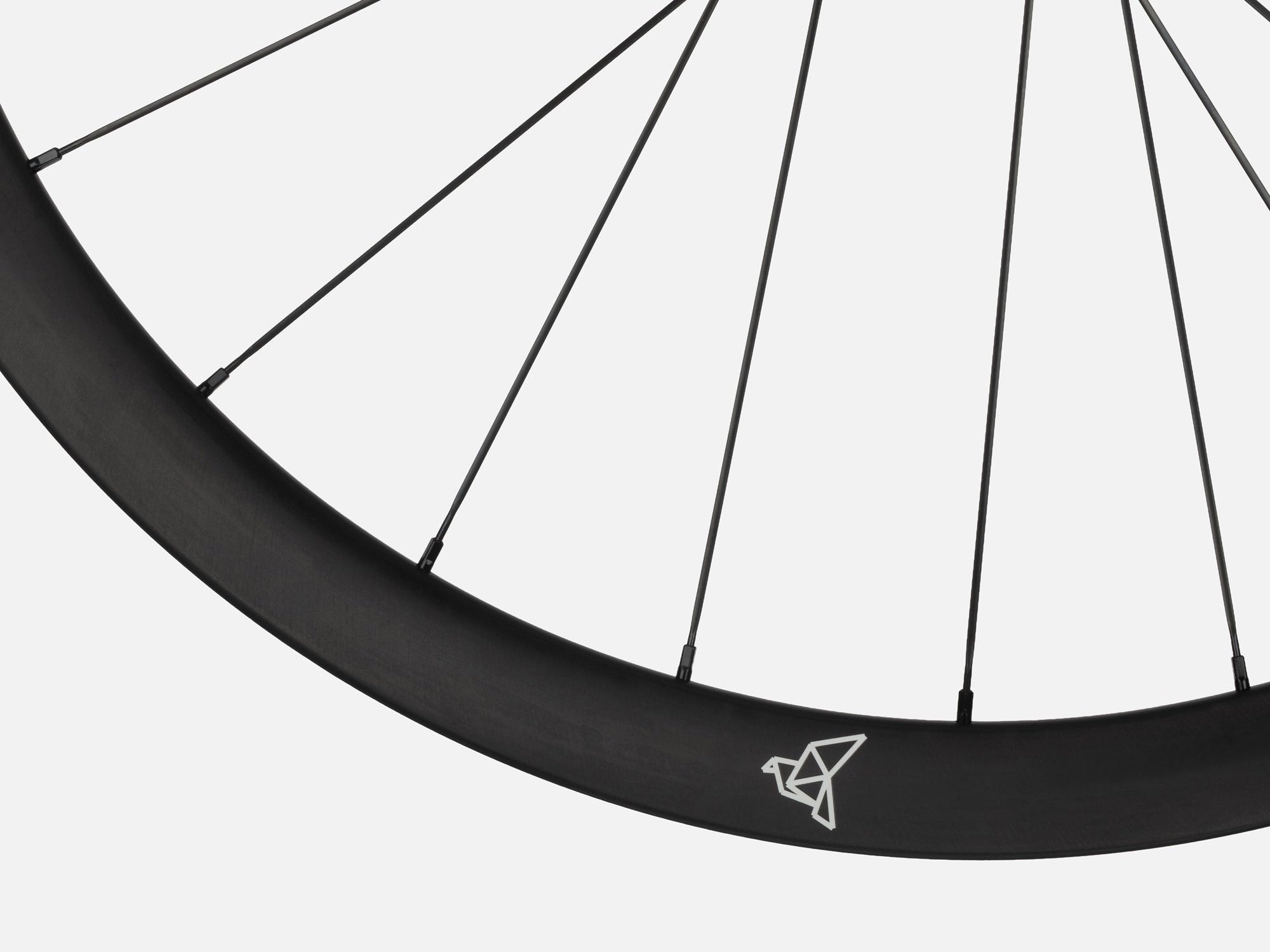 Close-up of Litebike Arc-35 carbon wheelset. A black bicycle wheel rim with thin black spokes and a small white geometric logo near the top, shown against a light gray background.